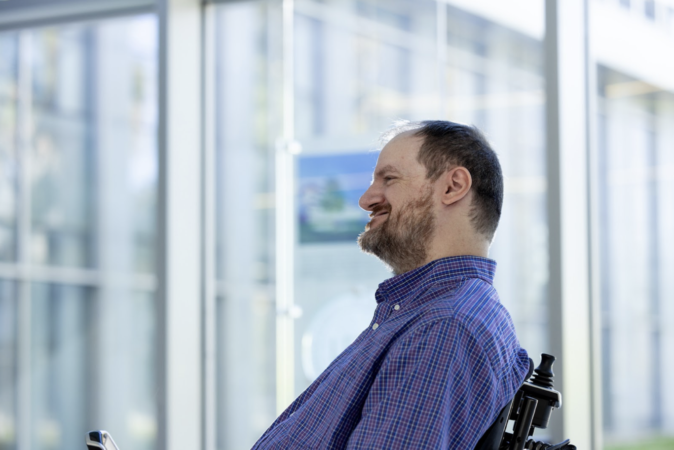 profile angle of non-ambulatory adult man with Becker muscular dystrophy smiling